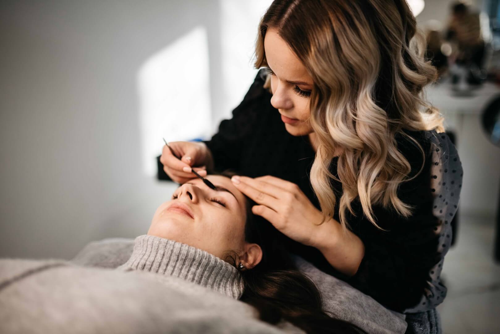 Stilistka obrvi med urejanjem strakinih obrvi.